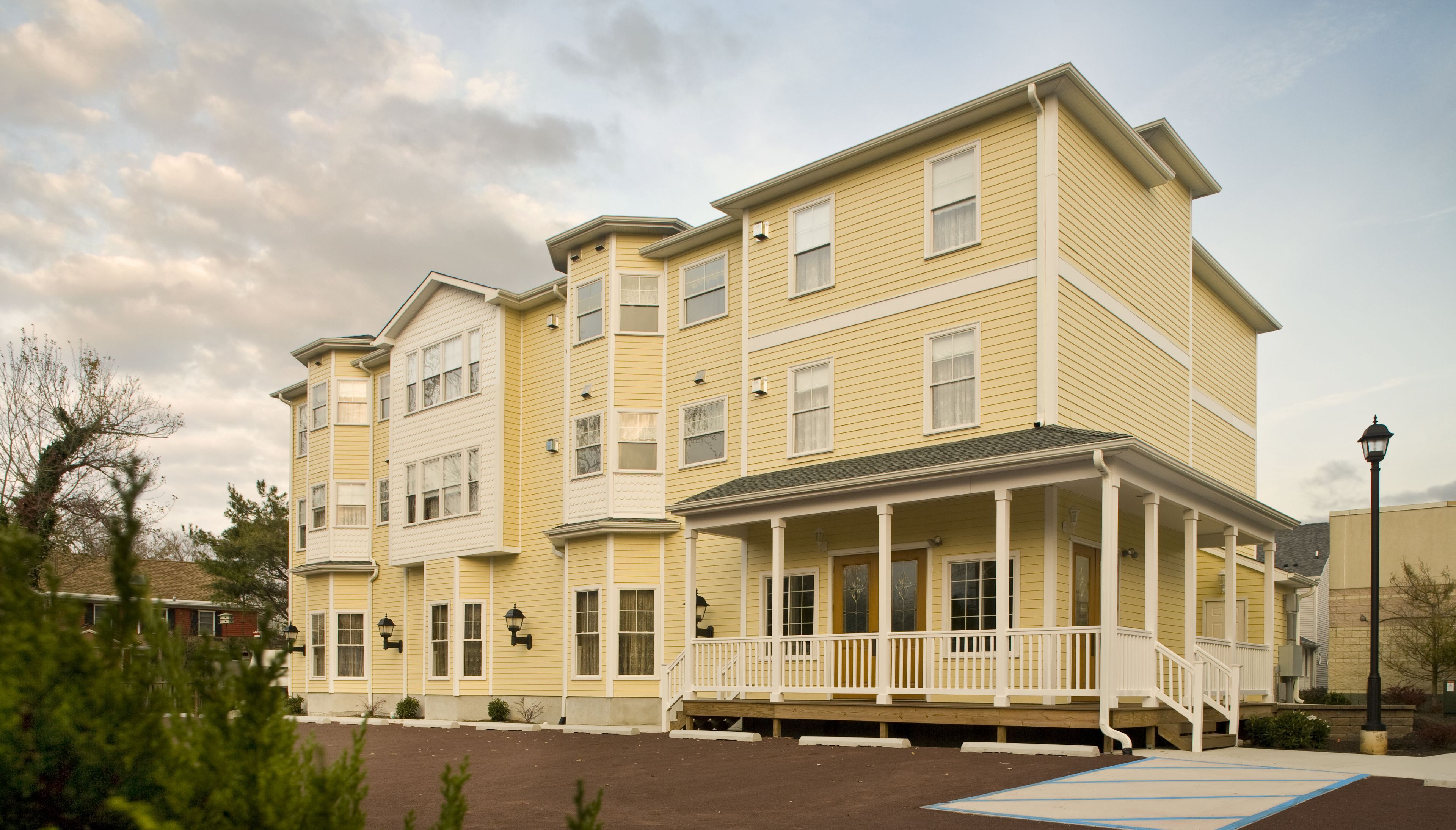 A multi-story yellow building with a covered porch and multiple windows.