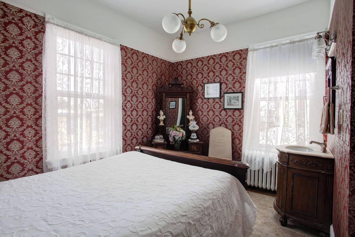 A bedroom with a large bed, a dresser, a mirror, and a radiator.