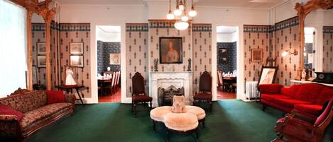 A formal living room with a green carpet, a fireplace, and a red sofa.