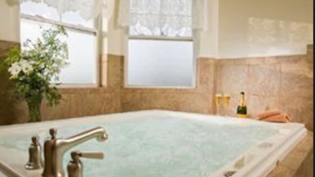Un jacuzzi grande y rectangular con un solo grifo, frente a una pared de azulejos color beige.
