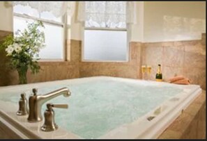 Un jacuzzi grande y rectangular con un solo grifo, frente a una pared de azulejos color beige.