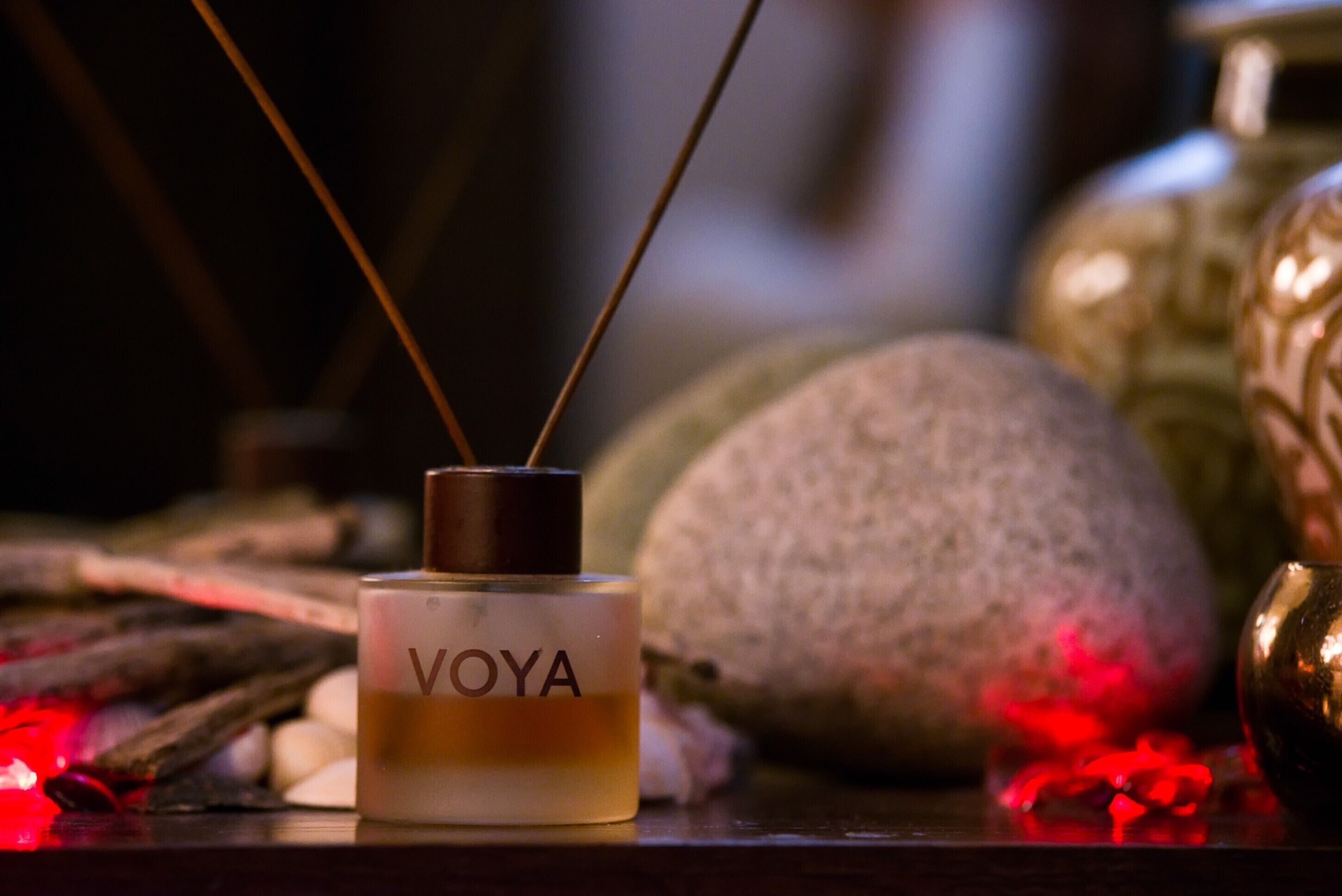 A bottle labeled "VOYA" on a wooden surface with decorative elements.