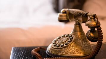 Een klassieke telefoon met draaischijf en gedetailleerde gravures op de voet, geplaatst op een donker oppervlak.