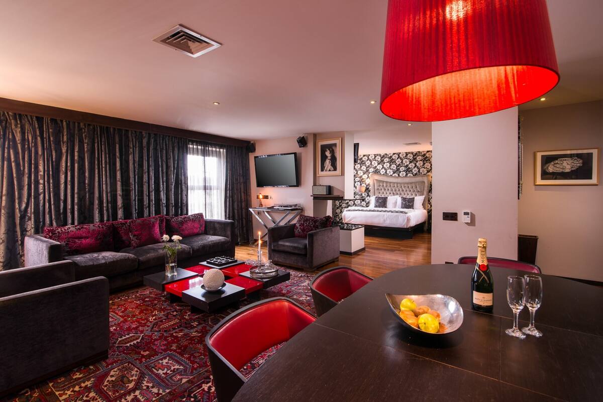 A modern hotel room with a living area, dining space, and a bedroom.