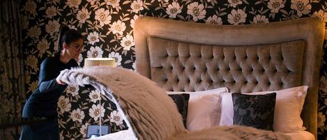 A bed with a tufted headboard, white bedding, and a large fluffy throw.