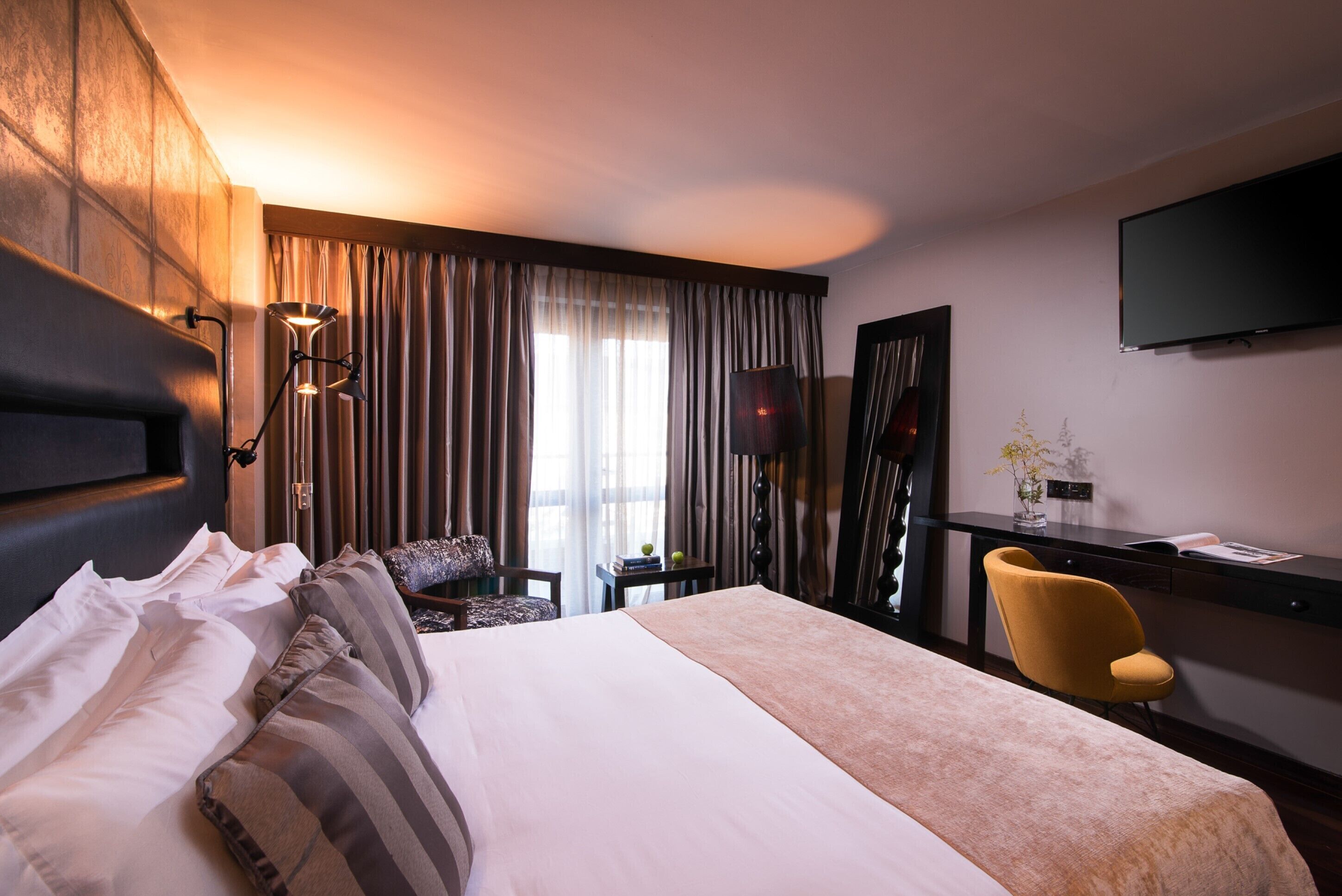 Habitación de hotel con una cama grande, un escritorio, una silla y un televisor.