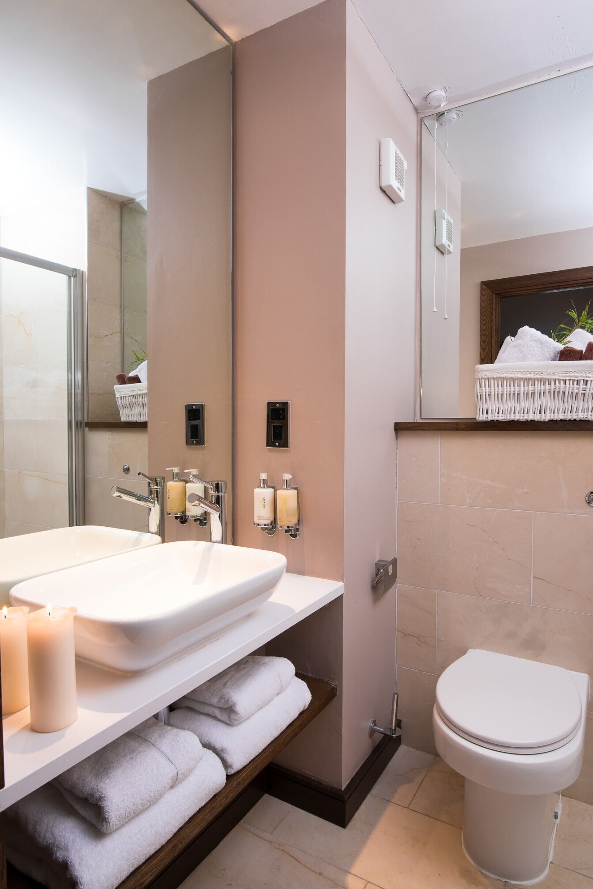 Une salle de bain moderne avec un grand miroir, deux lavabos, des toilettes et une douche.