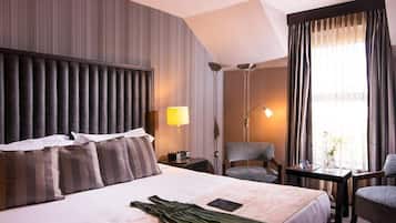 A hotel room with a large bed, a desk, a chair, and a lamp.