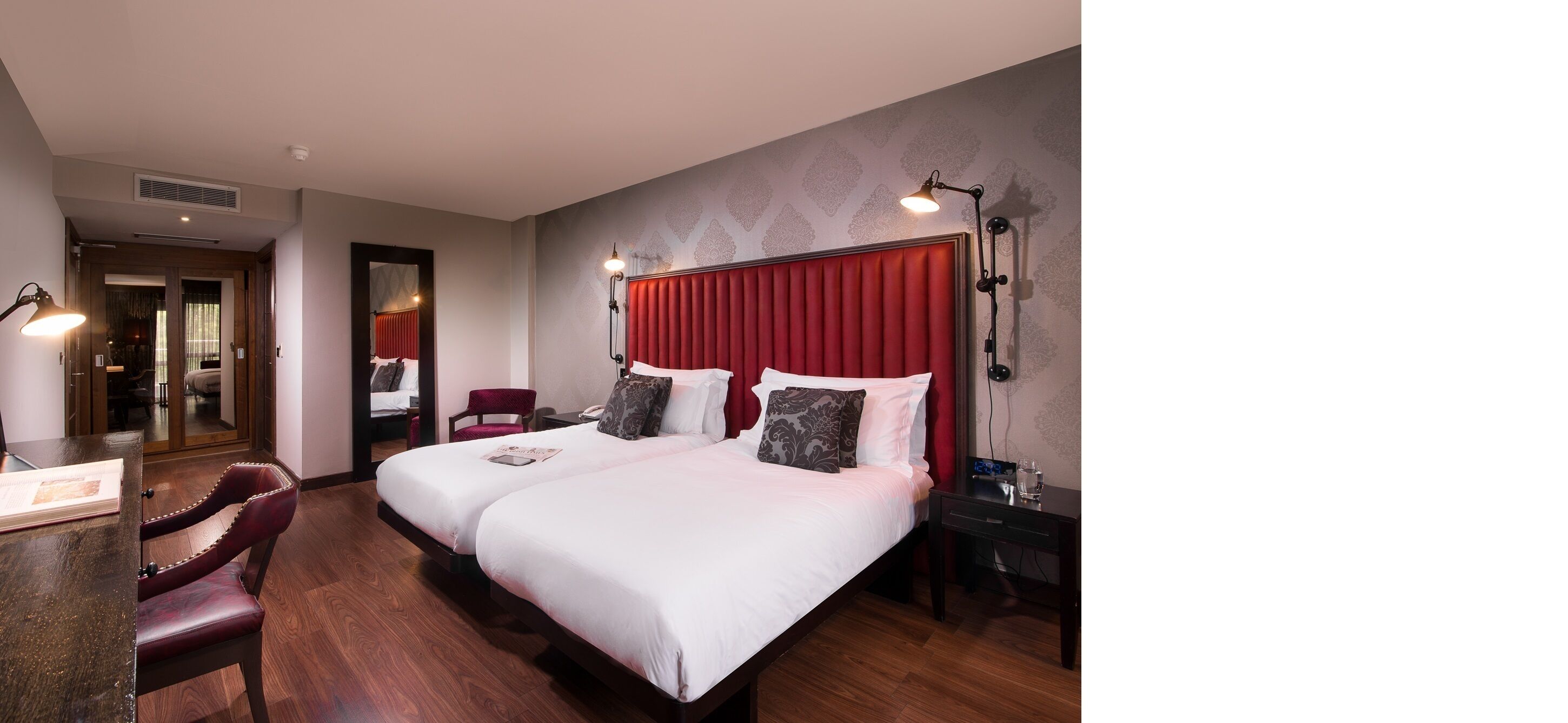 Een hotelkamer met twee bedden, een bureau en een stoel.