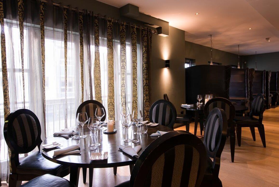 A dining area with a round table set for four, surrounded by chairs with striped upholstery.