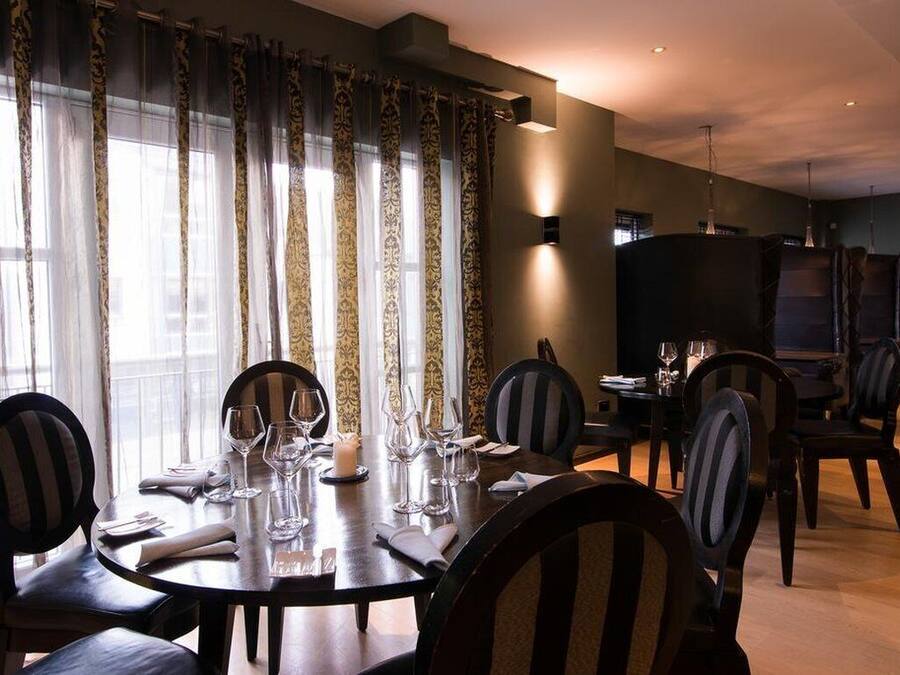 Comedor con una mesa redonda dispuesta para cuatro personas, rodeada de sillas con tapicería a rayas.