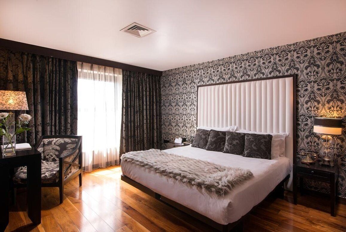 A bedroom with a large bed, a chair, a nightstand, and a lamp.