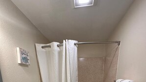 A bathroom with a shower, toilet, and vanity. - Rodeway Inn & Suites (Long Beach)