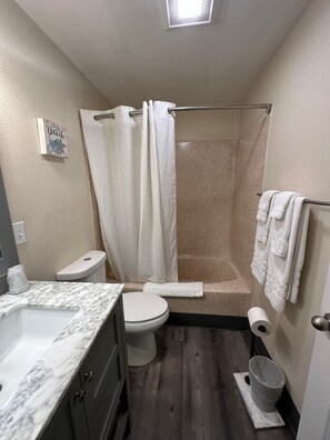 A bathroom with a shower, toilet, and vanity. - Rodeway Inn & Suites (Long Beach)