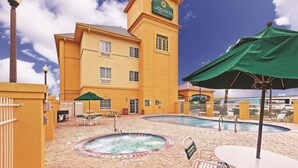 Een hotel met een zwembad, buitenterras en een bordje voor La Quinta Inn Suites.