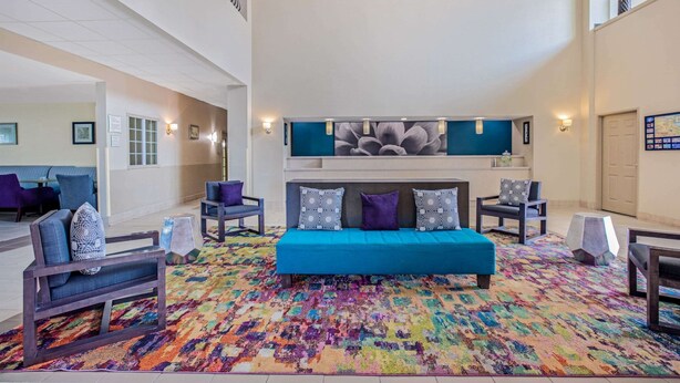 Een ruime woonkamer met een blauwe bank, meerdere stoelen en een kleurrijk vloerkleed.