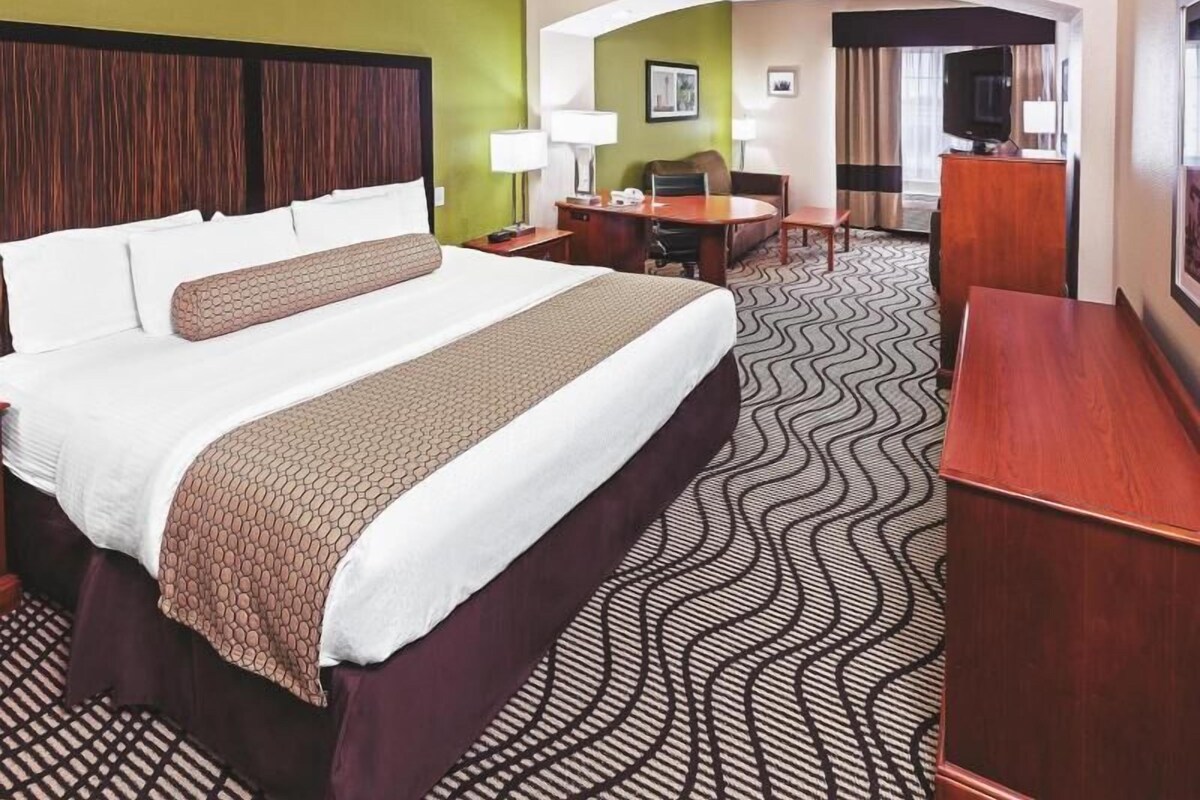 Une chambre d’hôtel avec un grand lit, un bureau, une chaise, une télévision et un coin repas.