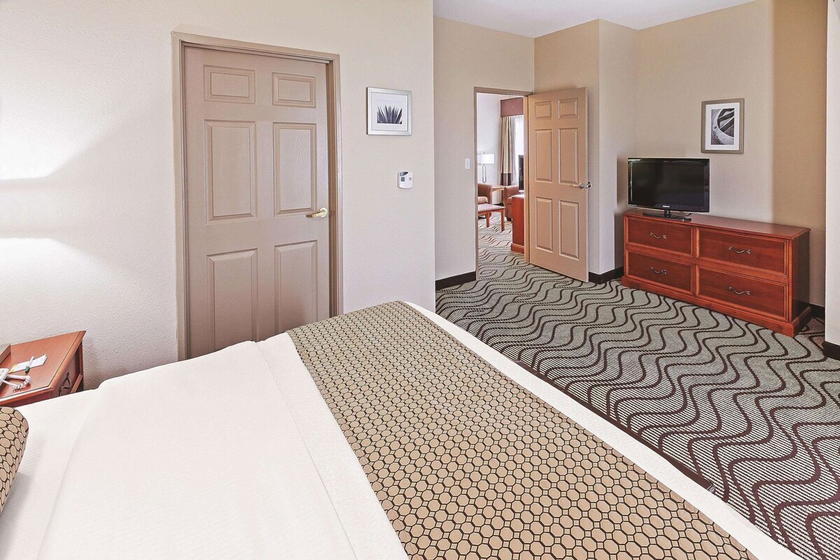 Une chambre d’hôtel comprenant un lit, une commode, un téléviseur et une porte donnant sur une autre pièce.
