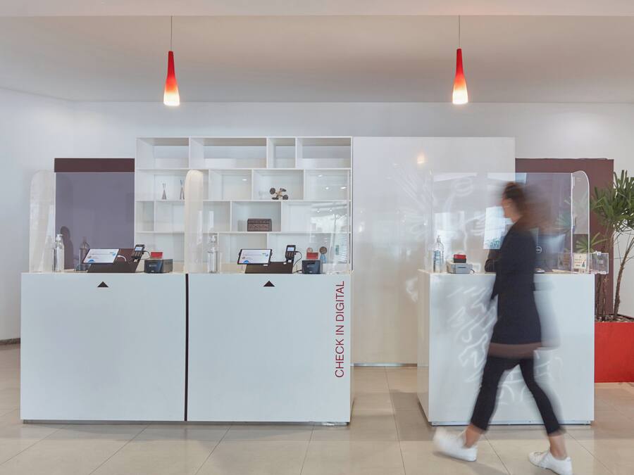 A reception area with a digital check-in station, a potted plant, and a modern interior design.
