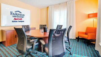 A conference room with a round table, four chairs, a coffee pot, and a sign for Fairfield Inn & Suites Marriott Durham/Southpoint.