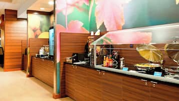Un área de bufé con un mostrador de madera y un llamativo muro floral.
