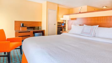 Une chambre d’hôtel avec un grand lit, un bureau équipé d’un ordinateur, une chaise et un four à micro-ondes.