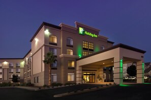 A Holiday Inn hotel building with a modern design, featuring a prominent green logo, multiple windows, and a covered entrance area. - Holiday Inn El Paso Airport by IHG (El Paso)