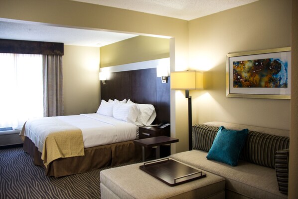 A hotel room with a bed, a sofa, a desk, and a painting on the wall. - Holiday Inn El Paso Airport by IHG (El Paso)