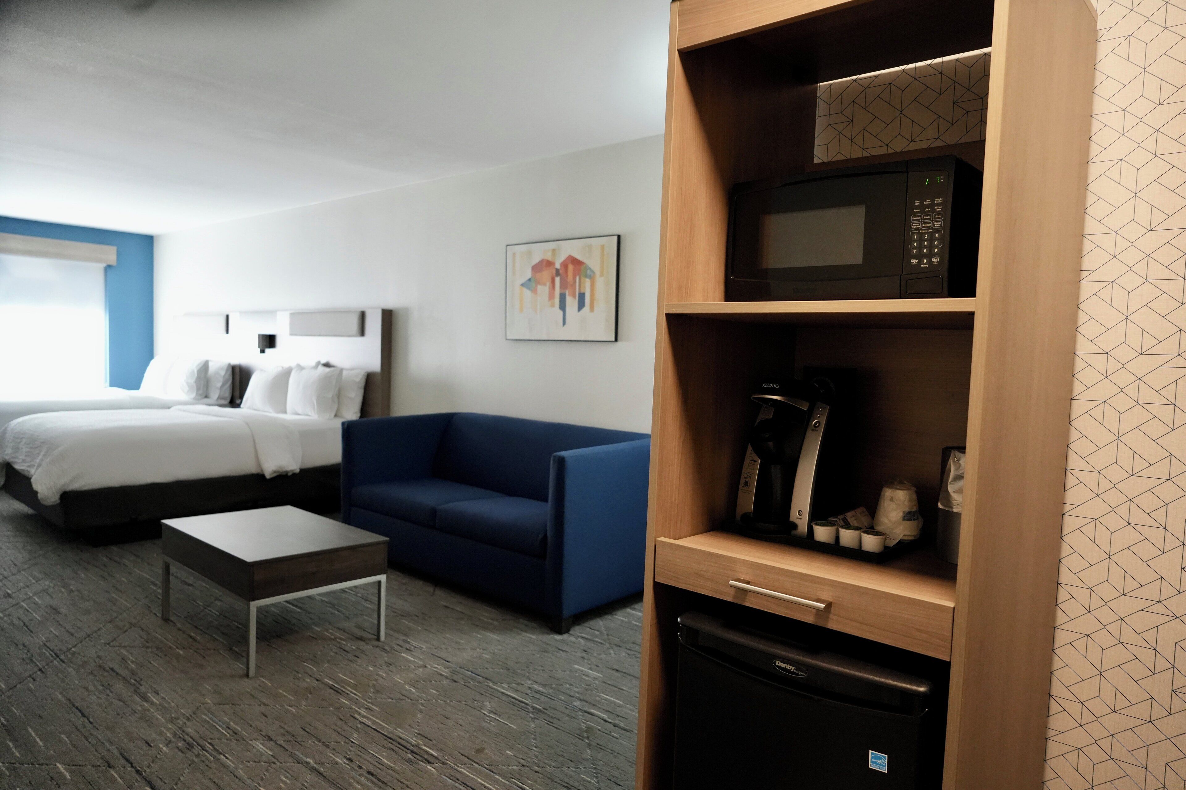 Ein Hotelzimmer mit Bett, blauem Sofa, Kaffeemaschine und Mikrowelle.