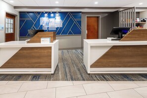 A reception area with two counters, a blue geometric wall design, and a carpeted floor.
