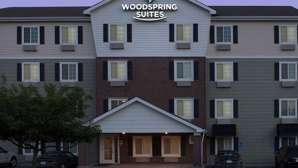 A multi-story hotel with a prominent sign reading 'WOODSPRING SUITES.' - WoodSpring Suites Kansas City Liberty (Liberty)