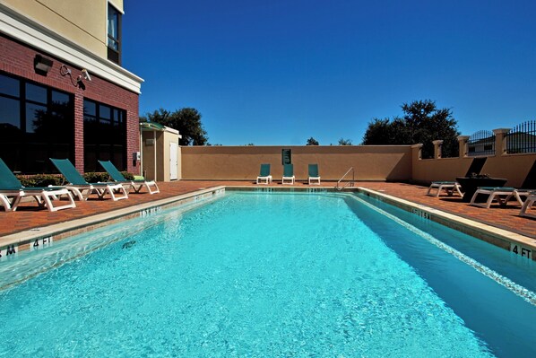 A rectangular swimming pool with clear blue water, surrounded by lounge chairs and a brick wall. - Holiday Inn Houma by IHG (Houma)