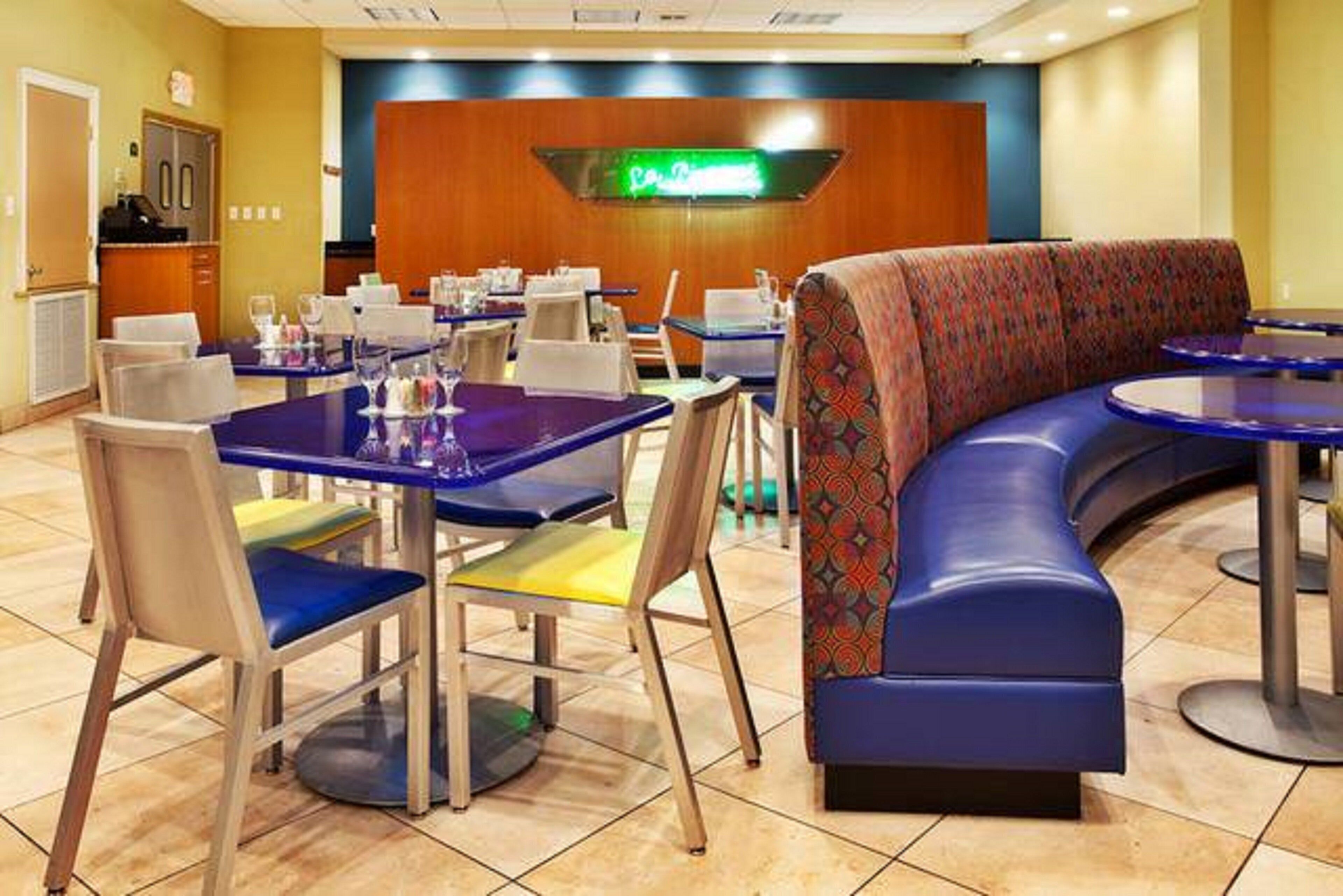 A restaurant with booths and tables, a counter, and a neon sign.