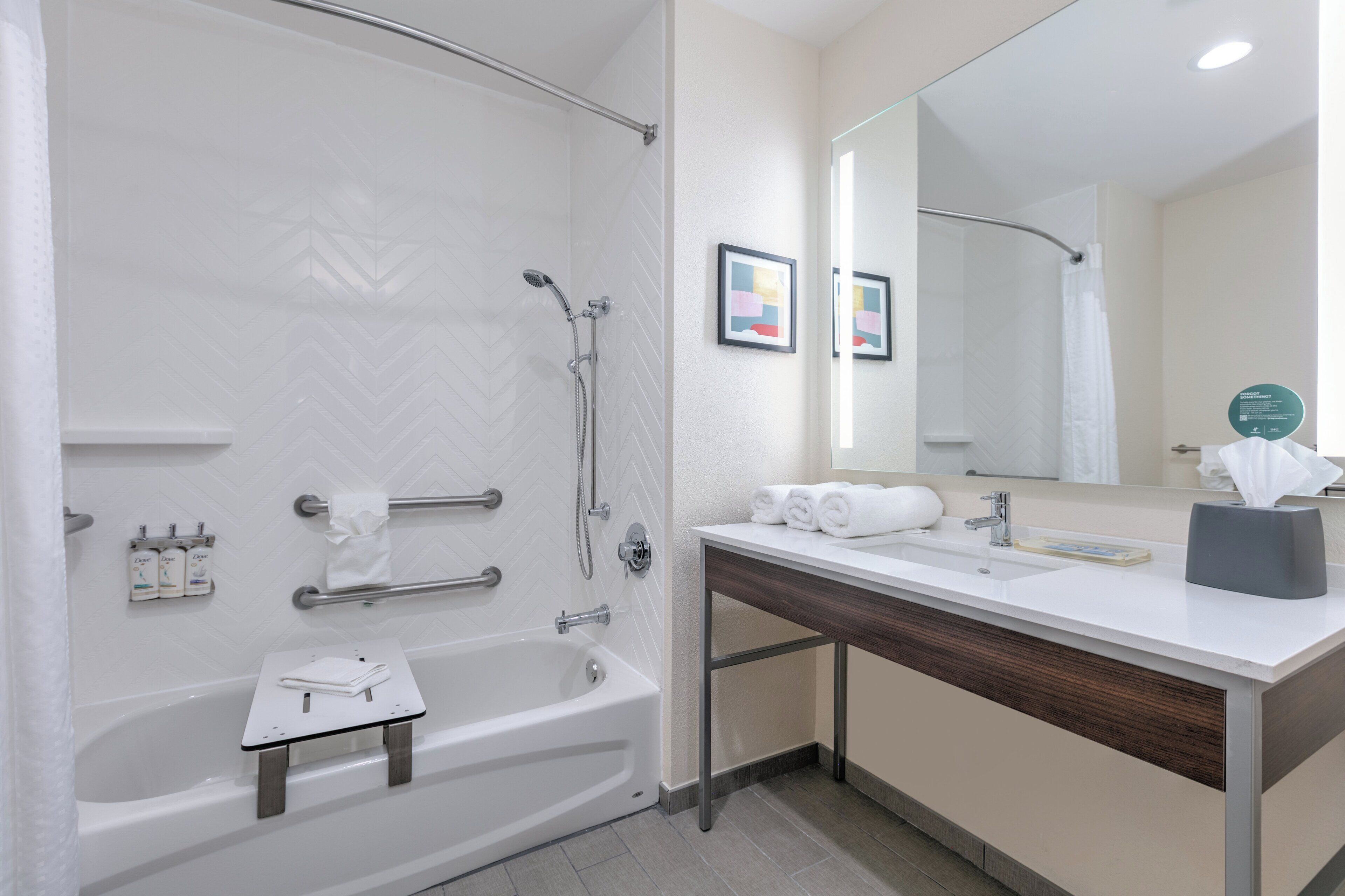 A modern bathroom with a bathtub, shower, vanity, and a large mirror.