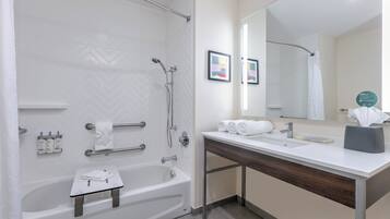 A modern bathroom with a bathtub, shower, vanity, and a large mirror.