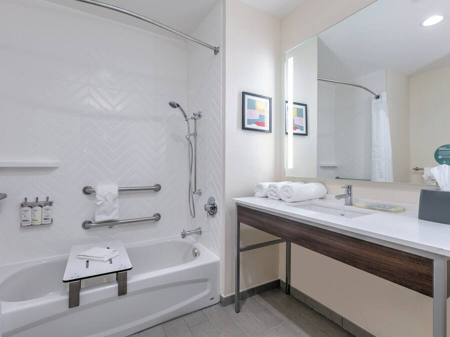 A modern bathroom with a bathtub, shower, vanity, and a large mirror.