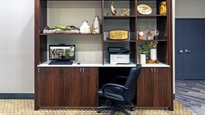 Un bureau en bois avec des étagères, un ordinateur et une chaise de bureau noire.