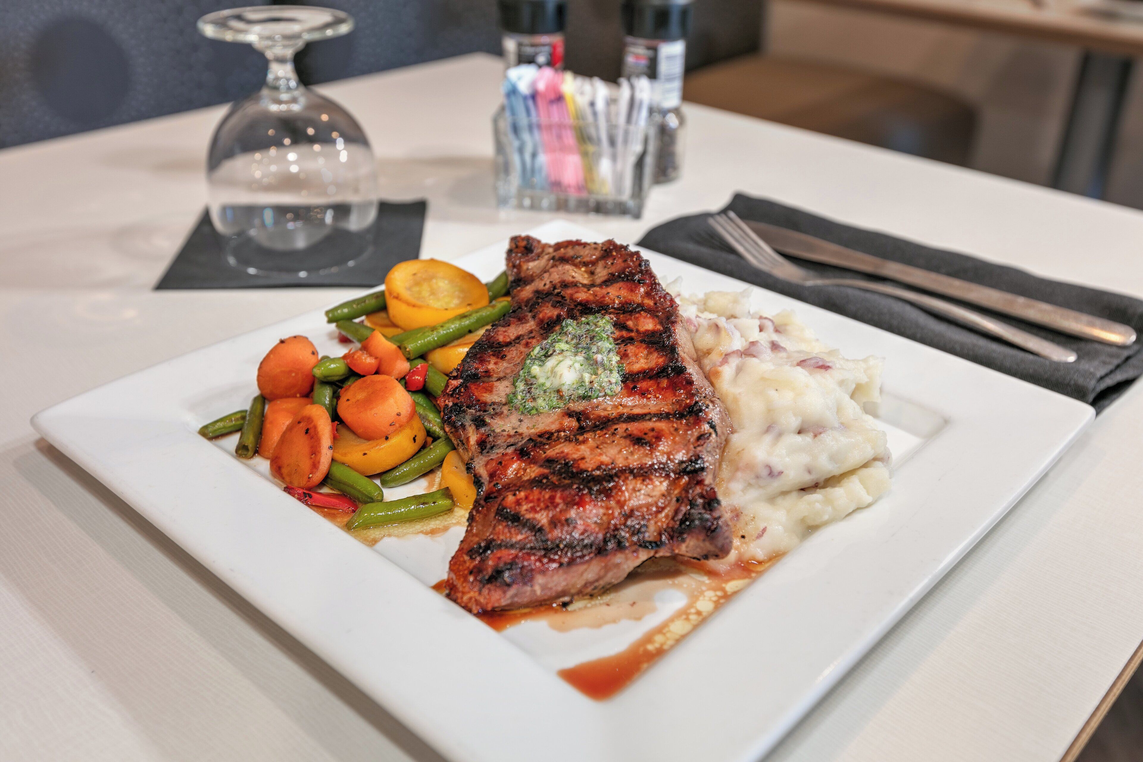 A plate of grilled steak with vegetables and mashed potatoes.