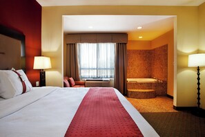 A hotel room with a large bed, a bathroom with a bathtub, and a view of the outdoors. - Holiday Inn Houma by IHG (Houma)