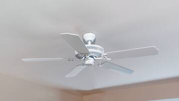 A ceiling fan in a room with beige walls and a visible window.