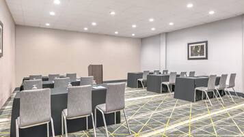 A conference room with tables and chairs, a patterned carpet, and a framed picture on the wall.