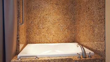A bathroom with a rectangular bathtub, a handheld showerhead, and a grab bar on the wall.