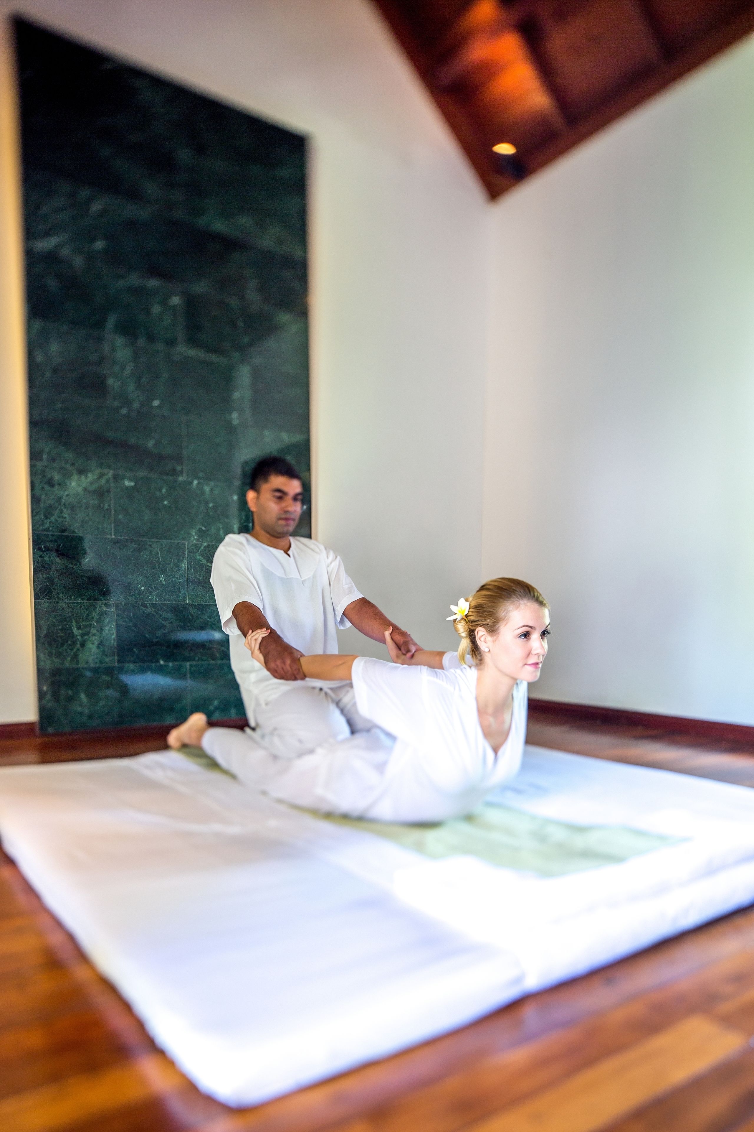 A room with a large dark textured wall, a wooden floor, and a white mat on the floor.