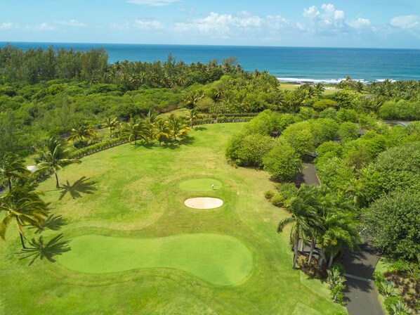 A golf course with a clear view of the ocean and lush greenery.