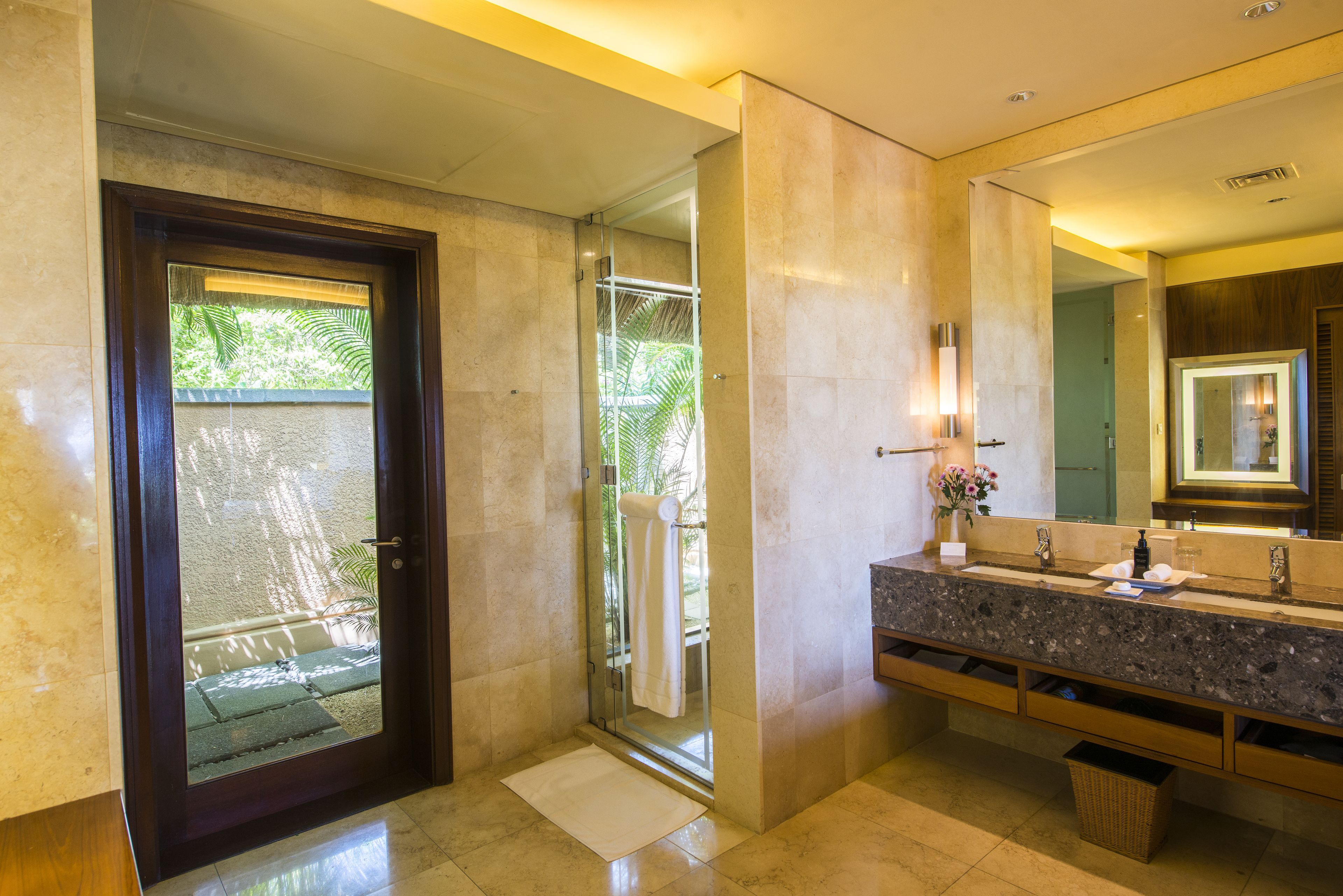 Un baño moderno con un espejo grande, encimera de granito y cabina de ducha de vidrio.