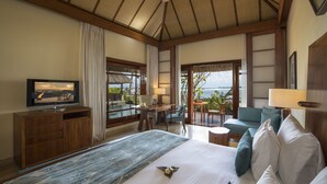A hotel room with a large bed, a TV, a desk with a chair, a balcony with a view, and a ceiling fan. - Shanti Maurice Resort & Spa (Chemin Grenier)