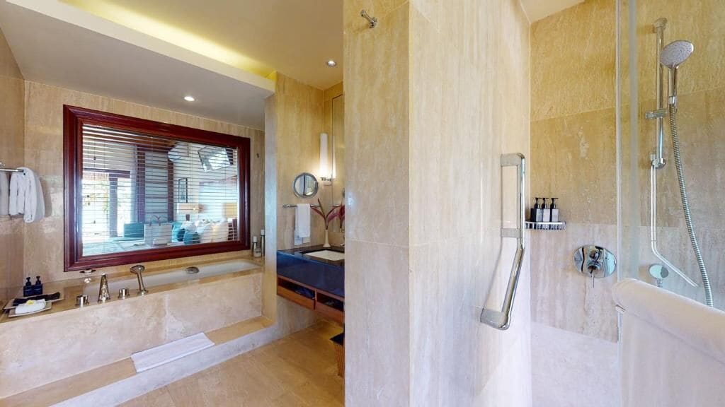 Un baño moderno con un espejo grande, una bañera, zona de ducha y tocador con lavamanos.