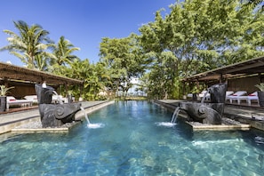 A clear pool with two waterfalls, surrounded by lounge chairs and palm trees. - Shanti Maurice Resort & Spa (Chemin Grenier)
