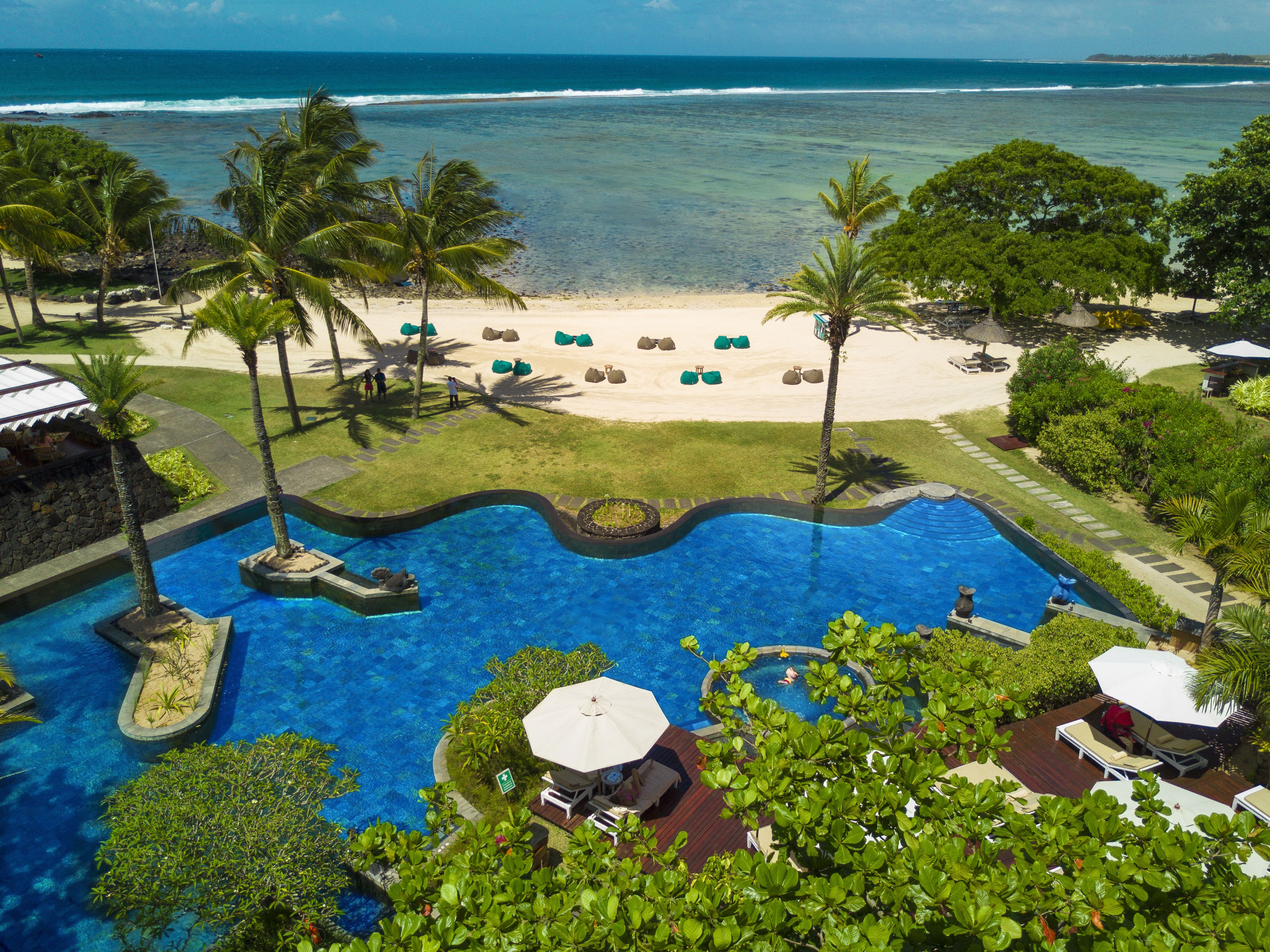 Un complexe hôtelier doté d’une piscine, d’une plage et offrant une vue sur l’océan.