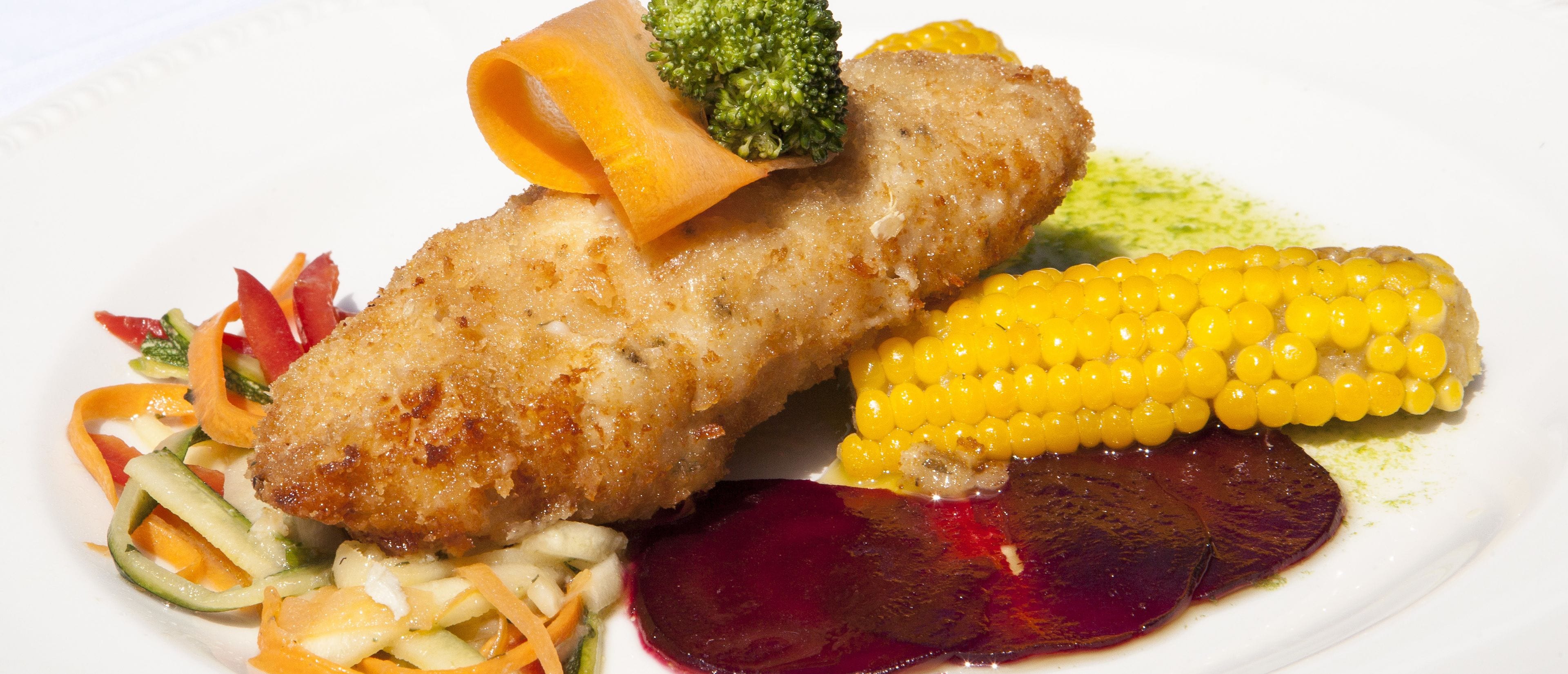 A plated meal with a breaded item, corn, and a beetroot slice.